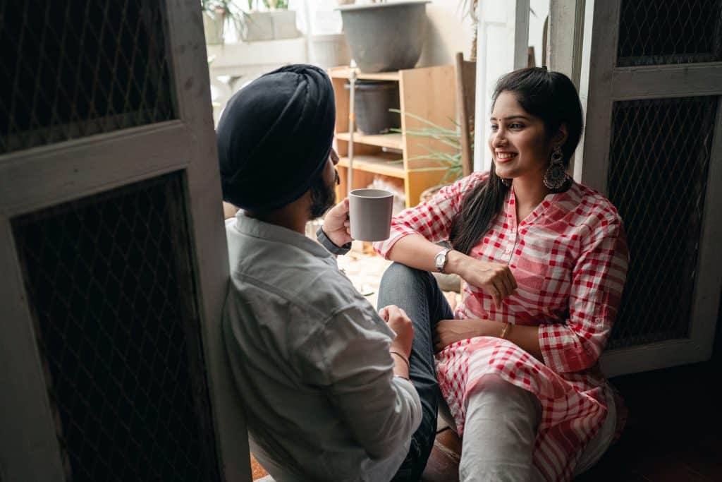 Couple sat in doorway chatting with a hot drink